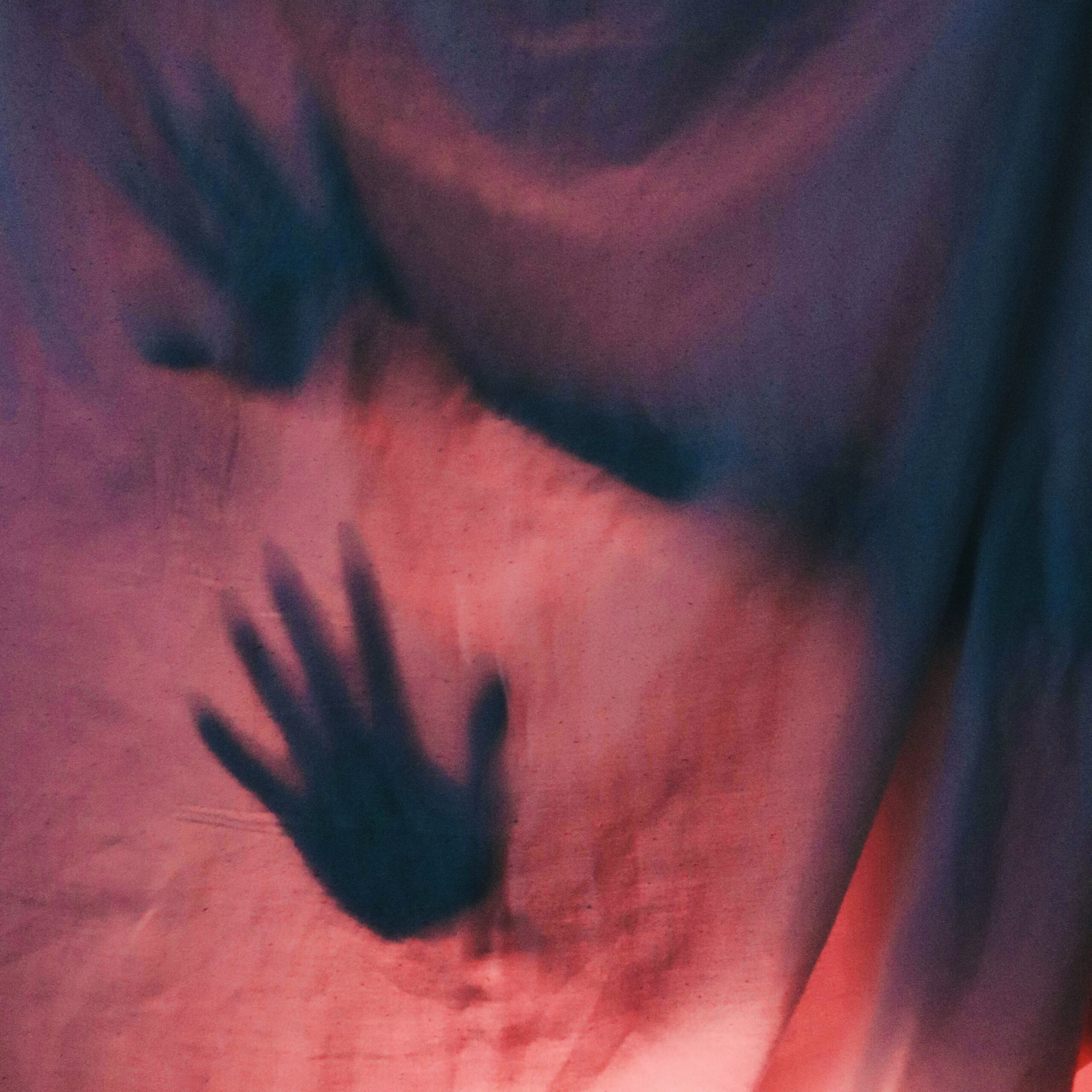 Hands pressing against pink sheet